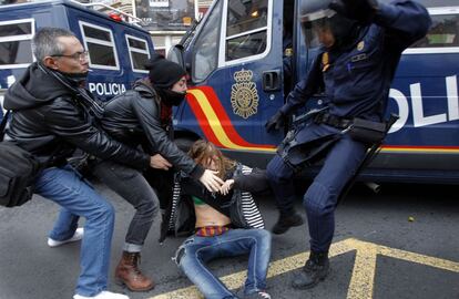 Un agente antidisturbios golpea a una manifestante durante la huelga general del 14-N en Valencia