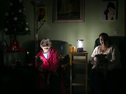 Dos mujeres iluminan con linternas el salón de su casa, en Barcelona en 2020.