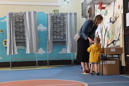 Una mujer y su hijo eligen las papeletas en el colegio electoral de Nuestra Señora de la Almudena de Madrid, este domingo. 