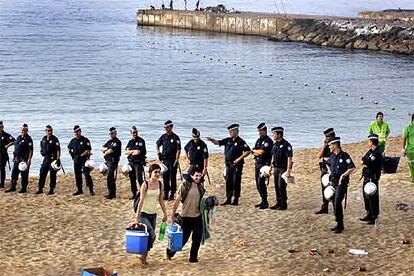 Cordón de la Guardia Urbana en la playa de Bogatell, ayer a primera hora de la mañana, para iniciar la limpieza.