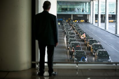 Un hombre oberva desde un ventanal a los taxis a su paso por el aeropuerto de Barcelona.