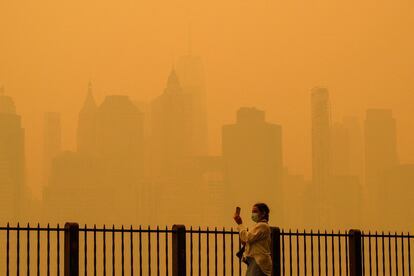 Una mujer con mascarilla fotografía el cielo de Nueva York el 7 de junio.