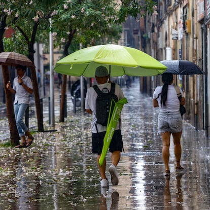 BARCELONA, 20/08/2025. -Una persona se protege con una sombrilla de playa de la tormenta caída a primera hora de la tarde en Barcelona, este miércoles, día en que Protección Civil de la Generalitat ha activado la alerta del plan INUNCAT ante la previsión de lluvias intensas a partir de las 14.00 horas de esta tarde y durante el día de mañana jueves en varios puntos del territorio. EFE/ Quique García