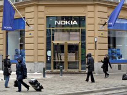 Varios viandantes pasan delante de una tienda que la fabricante de teléfonos móviles Nokia tiene en Helsinki (Finlandia).