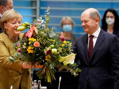 La canciller alemana en funciones, Angela Merkel, recibe un ramo de flores de su previsto sucesor, Olaf Scholz, esta mañana antes del que probablemente sea su último Consejo de Ministros.