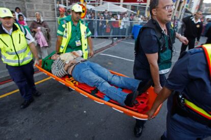 Operarios de emergencias retiran a uno de los heridos por la avalancha en la fiesta del Mundial en Ciudad del Cabo.
