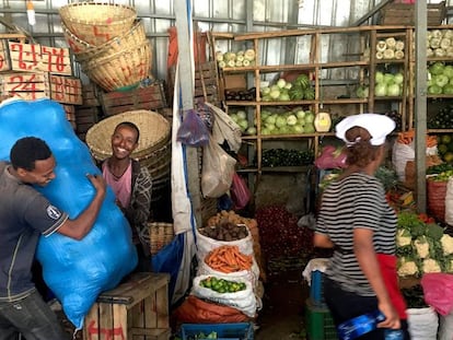 Una mujer con gorro blanco y delantal en el mercado de vegetales de Addis Abeba.