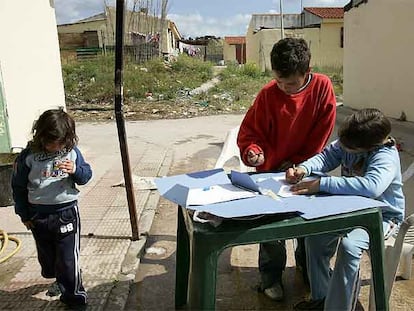 Dos niños hacen los deberes frente a su casa en el barrio malagueño de Los Asperones.