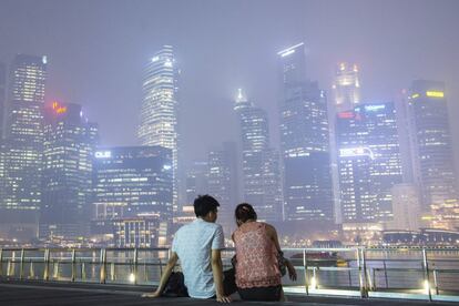 Una pareja observa los rascacielos cubiertos de humo en Singapur.