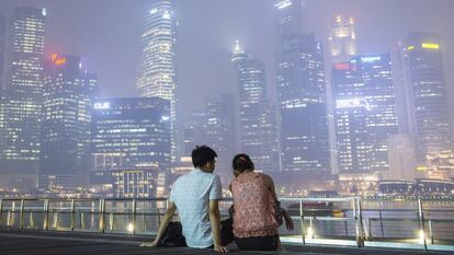 Una pareja observa los rascacielos cubiertos de humo en Singapur.