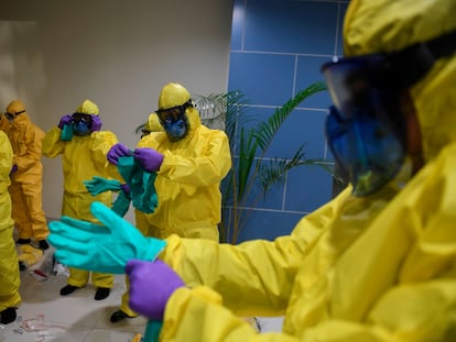 Técnicos vestem roupa de proteção para monitorar passageiros indonésios do cruzeiro Diamond Princess.