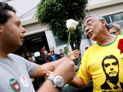Um eleitor de Fernando Haddad oferece uma flor a um eleitor de Jair Bolsonaro, durante a jornada de segundo turno em um colégio eleitoral de São Paulo.