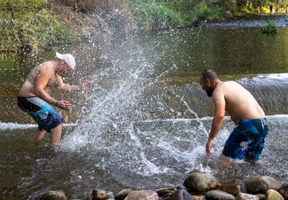 Dos hombres se refrescan en el río Iregua en Logroño, este sábado.