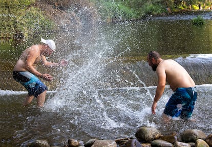 Dos hombres se refrescan en el río Iregua en Logroño, este sábado.