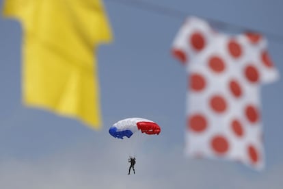Un paracaidista con los colores de la bandera francesa es fotografiado justo en el momento en el que pasa entre réplicas de los maillots colgadas en pleno tránsito de la ronda gala.
