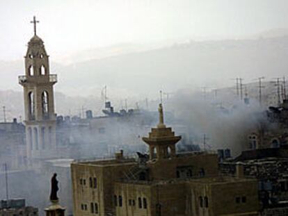 El humo provocado por los enfrentamientos ante la basílica de la Natividad se eleva sobre el campanario (izquierda).