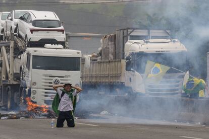 Un manifestante se arrodilla mientras la policía antidisturbios lanza gases lacrimógenos a los camioneros que bloquean una carretera en protesta por la derrota del presidente Jair Bolsonaro, en las afueras de São Paulo.