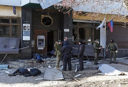 Policías y milicias prorrusas junto a los cuerpos de varios civiles tras un bombardeo en la ciudad de Donetsk, este lunes.