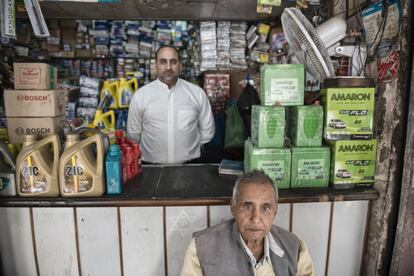 Jawahar, sentado, posa frente al mostrador del taller mecánico que ha abierto su hijo mayor, Rakesh. Éste asegura que seguirá dando apoyo a los desheredados que sufran quemaduras incluso tras la muerte de su padre.