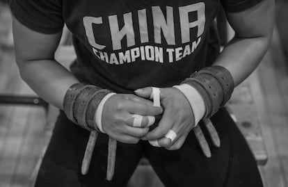 Una competidora femenina del equipo nacional chino de halterofilia protege sus manos con cintas durante un entrenamiento preparatorio para las Olimpiadas de Río 2016. Los levantadores de pesos normalmente entrenan seis días a la semana en el Centro de Entrenamiento de la Administración de Deportes en Pekín, China.