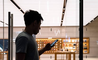 Un hombre revisa su teléfono frente a una tienda de Apple en Singapur