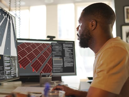 Close up stock image of an African American man working at a computer screen. He’s working on CAD software looking at the design of a solar panel array in CAD with data.