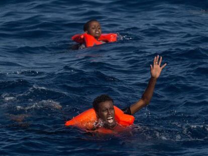 Dos náufragos subsaharianos piden auxilio tras zozobrar su embarcación cerca de la costa de Libia. / C. MCGRATH (GETTY IMAGES)