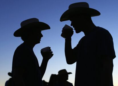 Dos fanáticos de la música country beben cerveza mientras cae la noche durante el último día del festival de música en Indio (California).