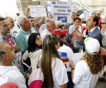 El presidente de Cantabria, Ignacio Diego (d), se detiene para hablar con afectados por las participaciones preferentes, a su llegada al palacio de La Magdalena, para acompañar a la vicepresidente del Gobierno, Soraya Sáenz de Santamaria, quien intervino hoy en la Universidad Internacional Menéndez Pelayo.