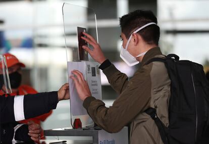Un pasajero escanea su pasaporte antes de abordar un avión en El Dorado, Bogotá