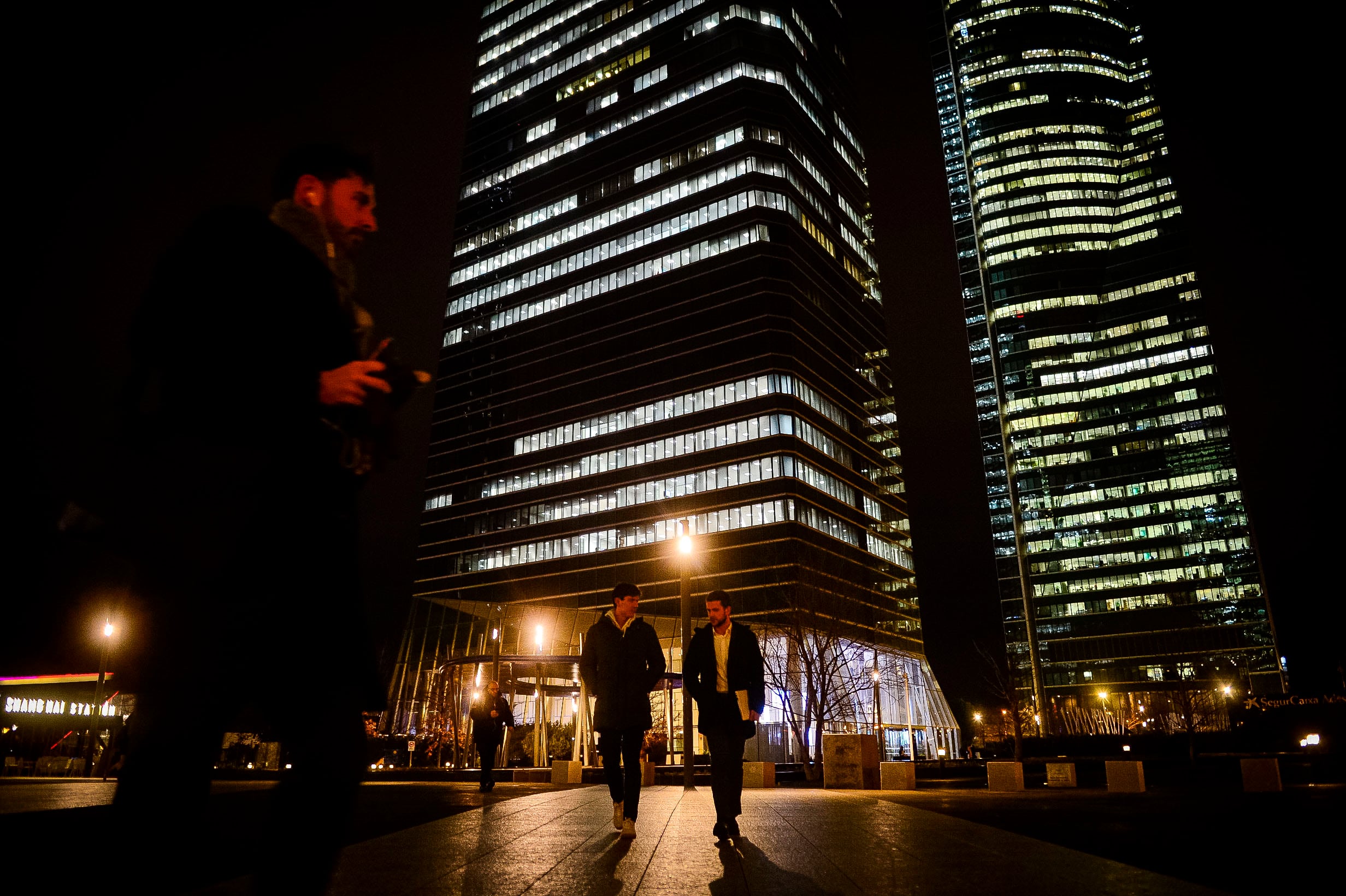 Varias personas en horario de salida del trabajo en la zona de las cuatro torres de la Castellana, en Madrid.