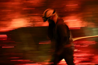 Bomberos forestales antes las grandes llamas del incendio en Aguasmestas, una parroquia del municipio de Quiroga, en la provincia de Lugo.