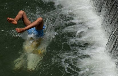 Un joven se refresca del calor en un río de Srinagar, India.