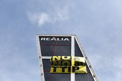 Una de las Torres Kio luce las dos pancartas colocadas por los activistas de Greenpeace contra el tratado de libre comercio entre EEUU y Europa, TPPI.