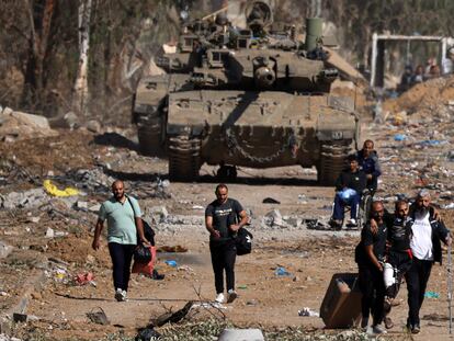 Varios gazatíes pasan ante un tanque israelí en las afueras de Ciudad de Gaza, en el primer día de la tregua entre Israel y Hamás, el 24 de noviembre.
