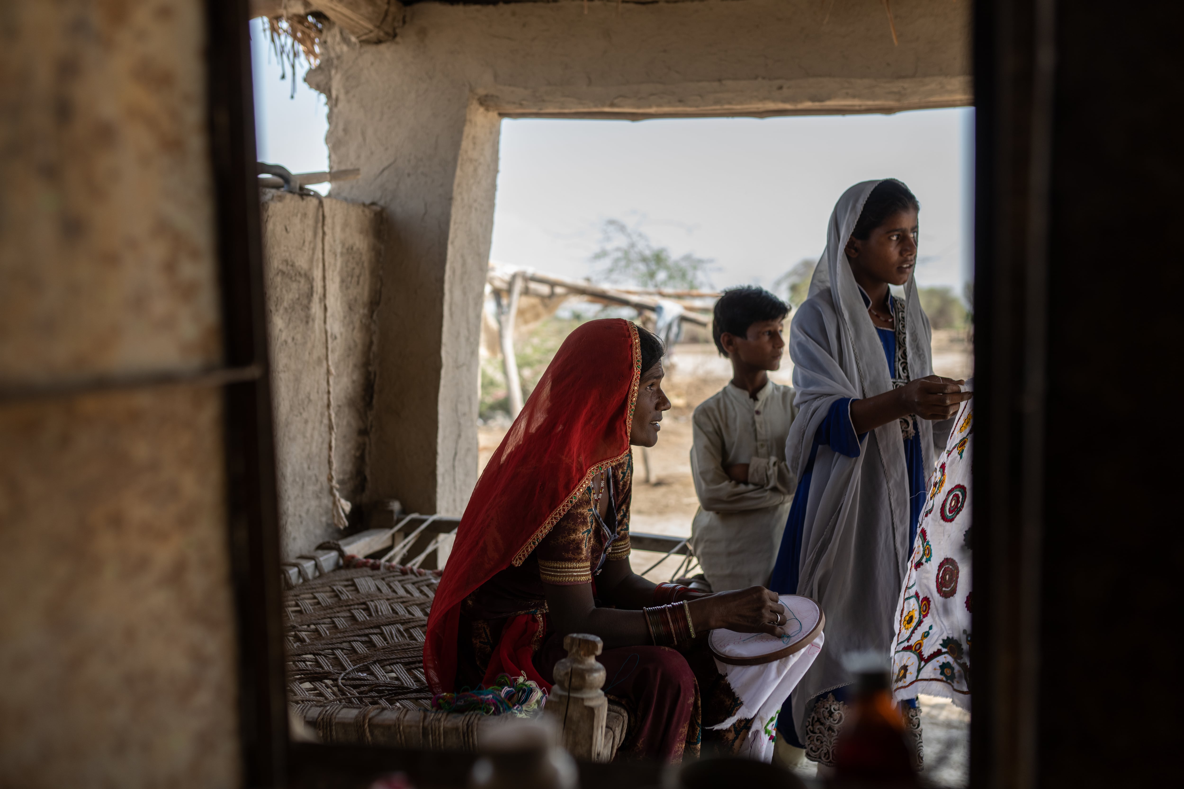 Kamli cose a la sombra de su porche, acompañada de sus hijos, en Umarkot, provincia de Sindh. El patio es el único lugar para guarecerse del calor abrasador. Estas paredes fueron reconstruidas tras las devastadoras inundaciones de 2022, en las que Kamli perdió su hogar y su única fuente de ingresos: la recogida de algodón en tierras que una vez fueron fértiles. Sobrevivió durante más de dos meses en campamentos temporales instalados en las carreteras de Umarkot. ''Vivimos con el miedo en el cuerpo, con la ansiedad de no saber cuándo será el próximo desastre. Esta es la única tierra que conozco. Mis antepasados son de aquí, nosotros trabajamos esta tierra y yo quiero quedarme aquí. No hay otra opción”, asegura bajo la atenta mirada de sus hijas. Su vida no era fácil antes de las inundaciones. Kamli enviudó con siete hijos a los que alimentar cuando su esposo murió de una enfermedad hepática hace cuatro años. En 2011 ya había sufrido la pesadilla de una inundación cuando estaba embarazada de seis meses y tuvo que ser evacuada para dar a luz en la casa de un pariente. Después de las lluvias, sus hijos tuvieron que ponerse a trabajar en los campos de algodón, ganando solo 45 euros al mes para mantener a toda la familia. 