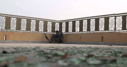 Un policía afgano se parapeta mientras toma posiciones en un edificio cercano tras el ataque contra la sede de la ONG Save the Children en Jalalabad (Afganistán).