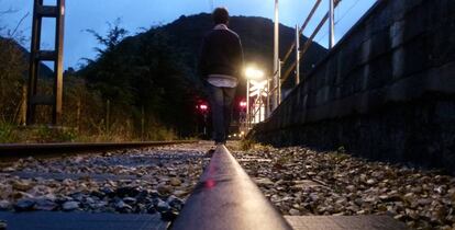 Un adolescente camina por una vía del tren.