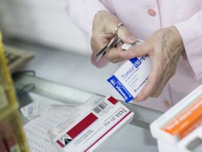 Una farmac&eacute;utica sirve medicamentos a unos clientes en una botica de Barcelona. 