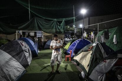 Um refugiado segura um bebê em um acampamento improvisado em Lebos.