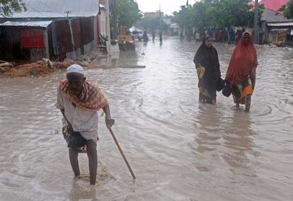 Varias personas caminan por una calle inundada de Mogadiscio tras las fuertes lluvias caídas durante la noche.