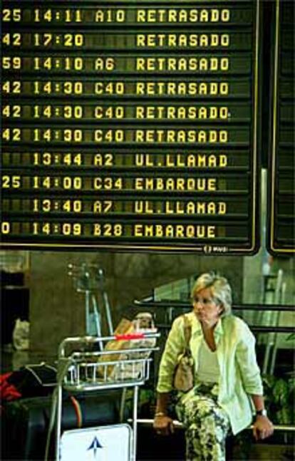 Una pasajera, ante el panel de información de vuelos en Barajas.