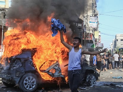 Un joven palestino junto a un vehículo israelí incendiado tras ser trasladado a Gaza por milicianos, este sábado.