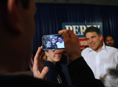 El candidato a las primarias republicanas, Rick Perry, se hace una foto con dos simpatizantes en Carroll, Iowa.