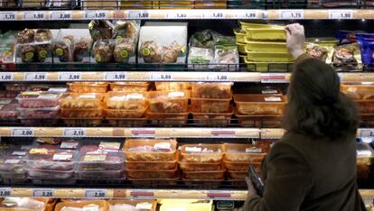 Una mujer elige productos cárnicos en un supermercado.