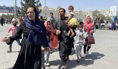 Una familia afgana corre hacia el aeropuerto internacional Hamid Karzai, en Kabul, este lunes.