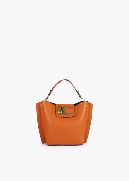 Como suele ser habitual en los accesorios de Lola Casademunt los colores y los detalles están especialmente pensados para marcar la diferencia y tomar las riendas de tu look. Este bolso, disponible en naranja, rosa chicle y negro, decorado con un leopardo de metal y la C es un buen ejemplo. (109 euros).