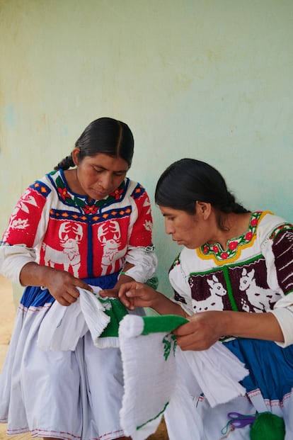 Las artesanas Irma Silva Vásquez y Marcelina Santiago González bordan una falda y una chaqueta blanca con la técnica del pepenado fruncido, típica de la región de San Lucas Redención, en Oaxaca, México.