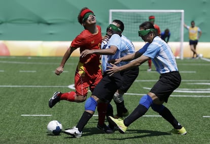 El chino Zhoubin Wang (i) lucha por el balón del argentino Federico Accardi (c) y Froilan Padilla durante la preliminar de fútbol. 