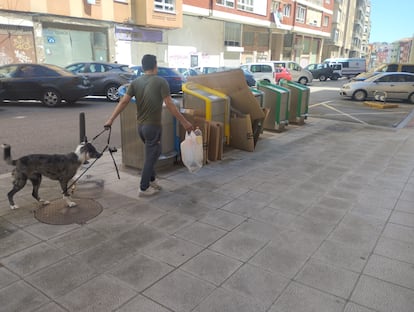 Un vecino con su perro va a tirar la basura en una calle de Santander.